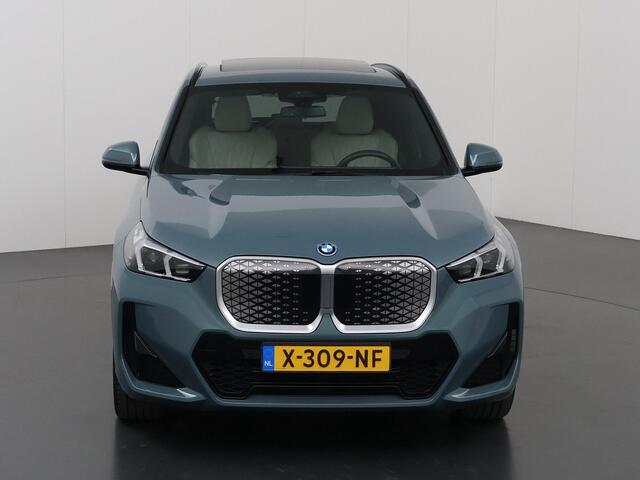 BMW iX1 eDrive20 67 kWh M-Pakket | SOH 98% | Panormadak | Sportstoelen | Curved Display | Harman/Kardon | Camera | Apple CarPlay/Android Auto | Ele.verstelbare stoelen + Geheugen | Ele. kofferdeksel |